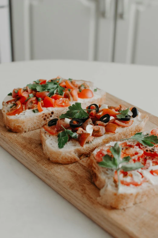 a wooden tray that has small pieces of bread with food on it