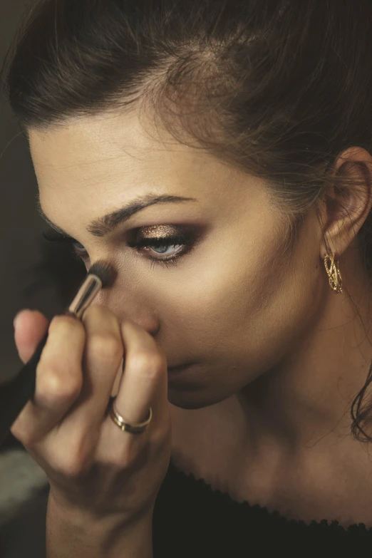 a young woman is putting on lipstick with an eyeliner