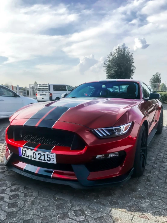 a red mustang parked in front of some other cars