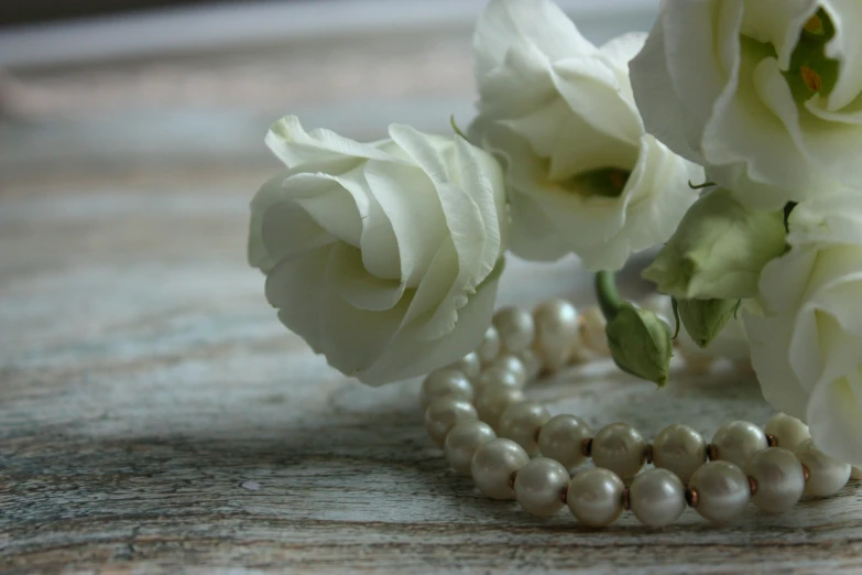 two celets with pearls next to flowers