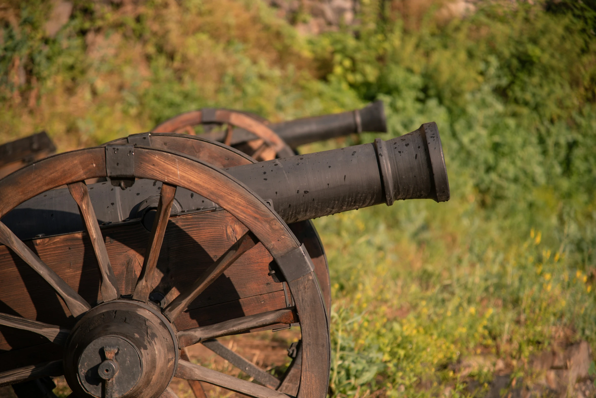 an old cannon sitting in a field next to green grass