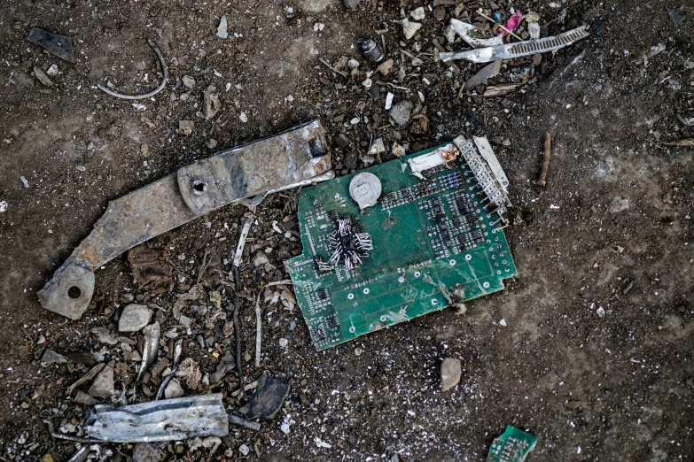 a broken green electronic board and wires on the ground