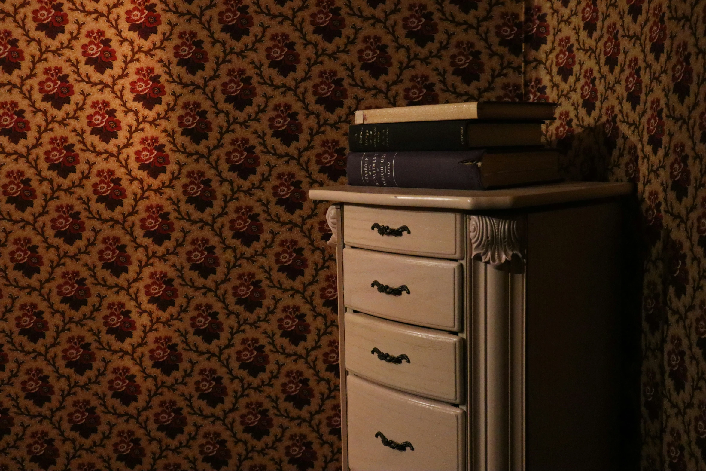 the tall dresser is next to a patterned wall