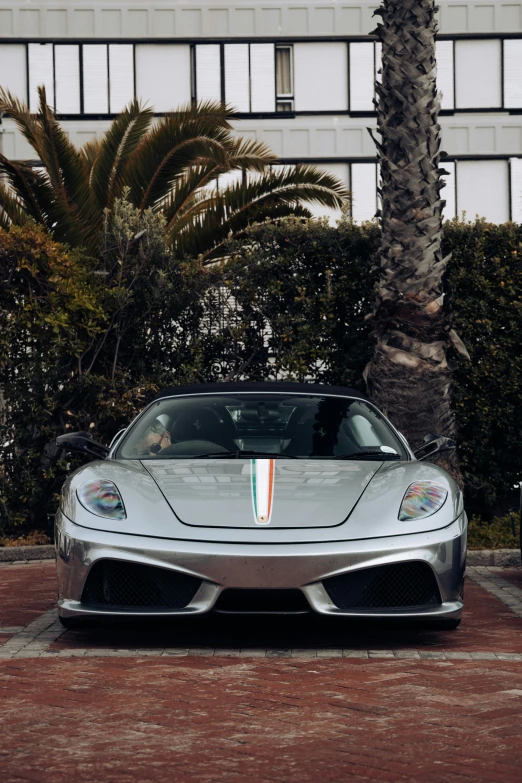 this silver sports car has stripes painted on the hood