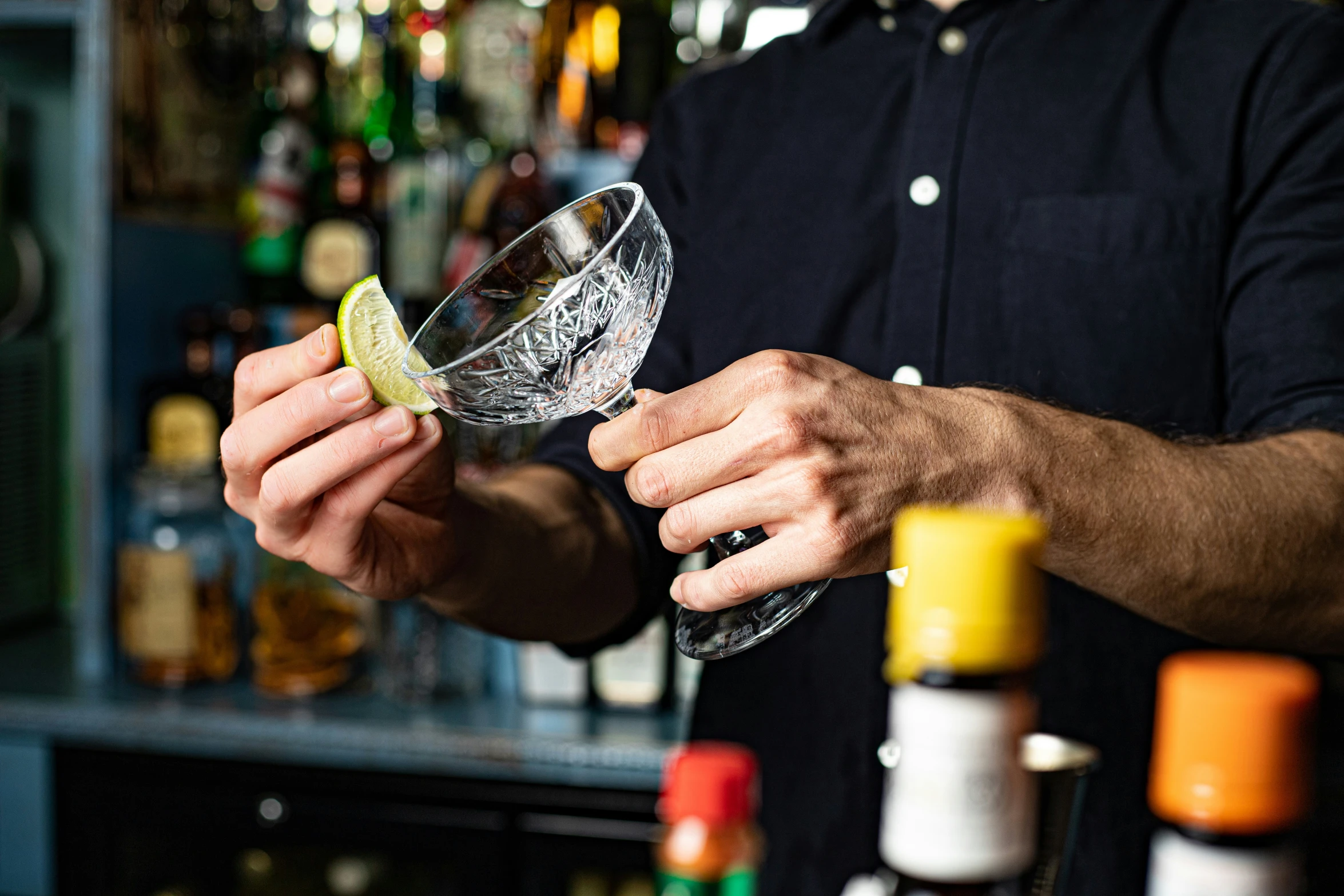 someone holds a wine glass with a lime wedge