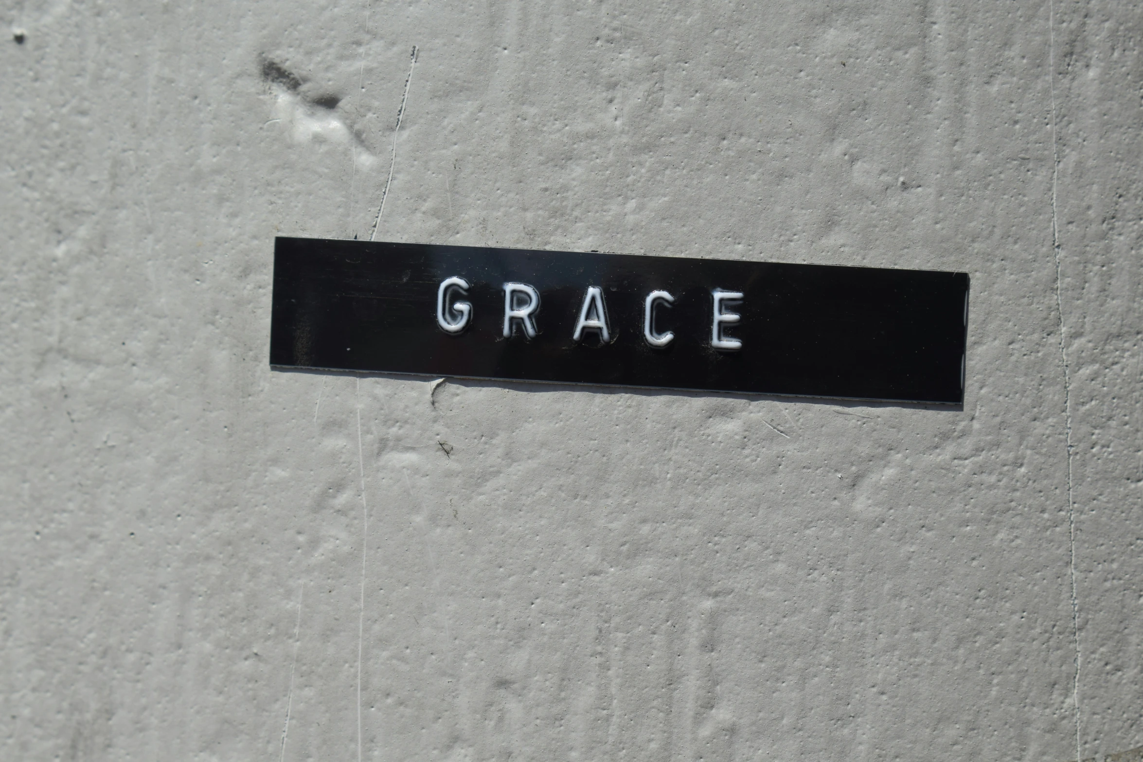 a sign that says grace on a grey wall