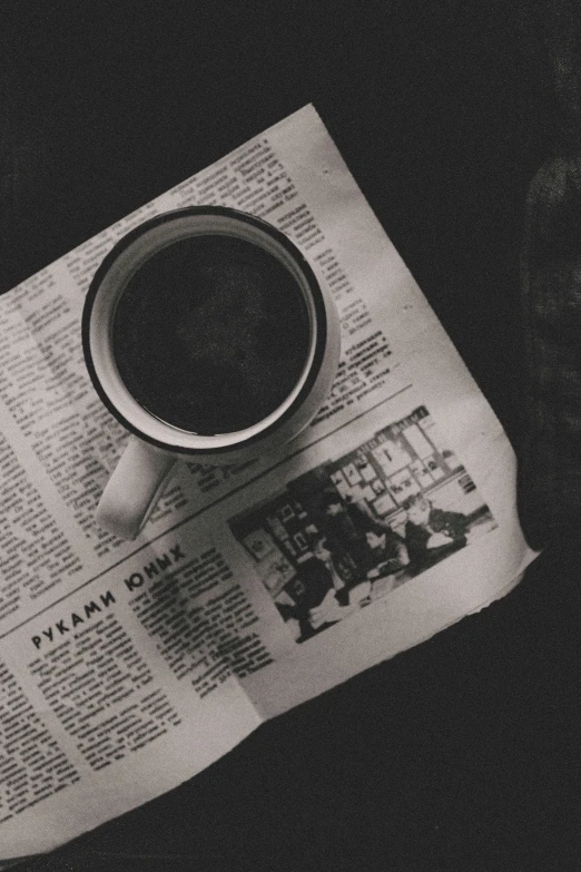 a newspaper on a table with a cup of coffee