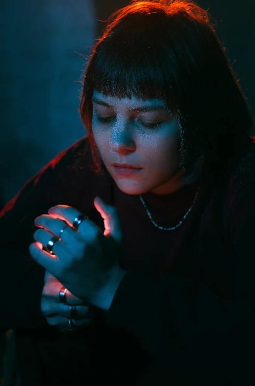 a woman with her eyes closed sitting down while looking at her cell phone