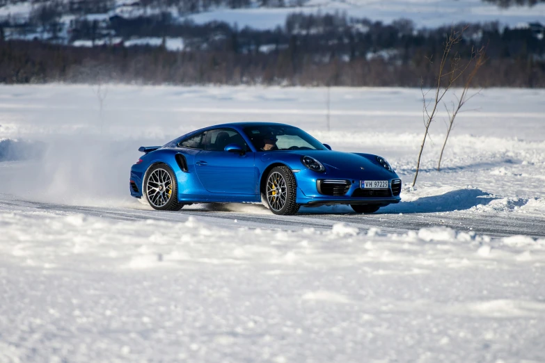 a blue car driving in the snow on the road