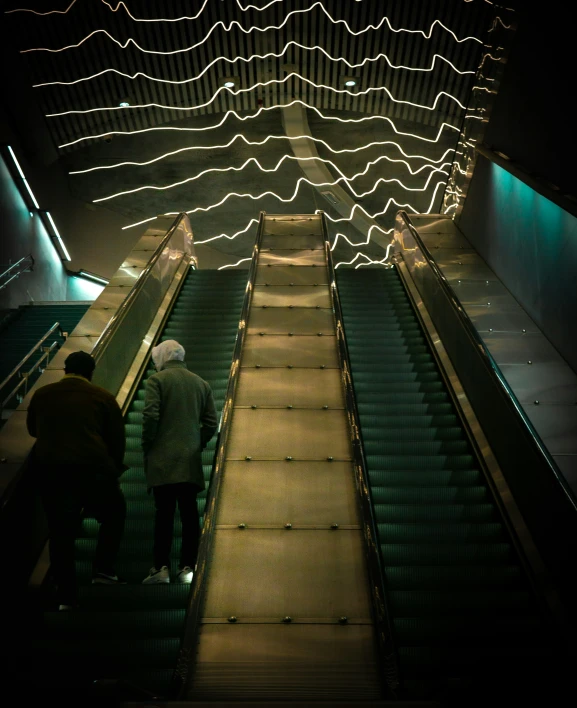 people are descending on an escalator lit up at night