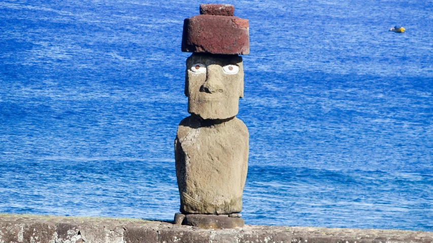 a statue on the beach with a hat on its head