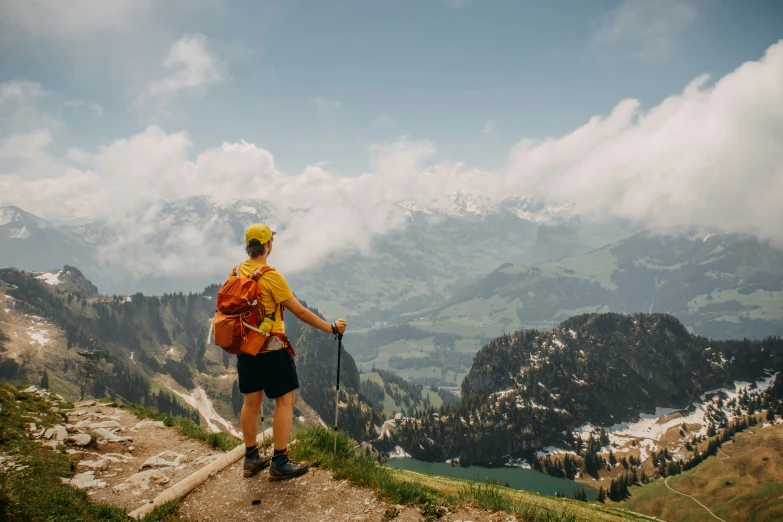 a man with a backpack is standing on the edge of a cliff overlooking mountains