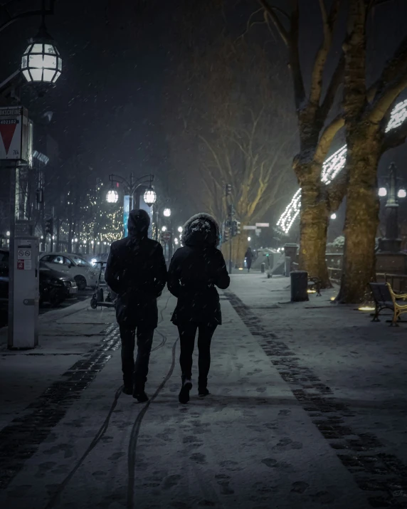 two people are walking down the street at night