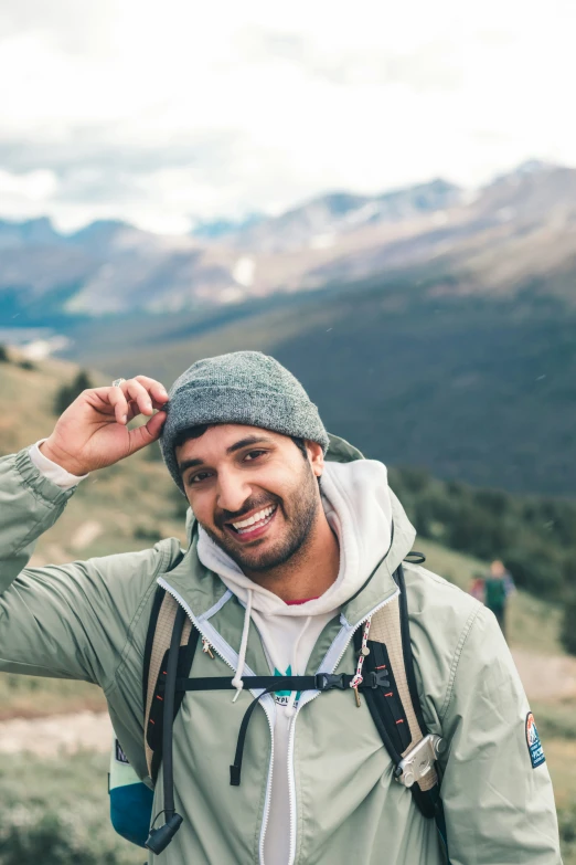 a man smiles while standing near a mountain range