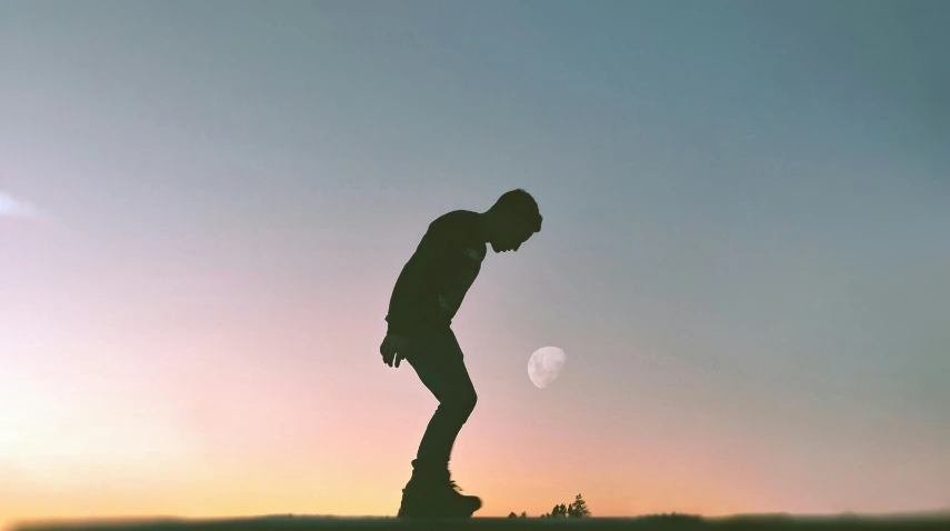 the silhouette of a skateboarder doing a trick against a bright sky