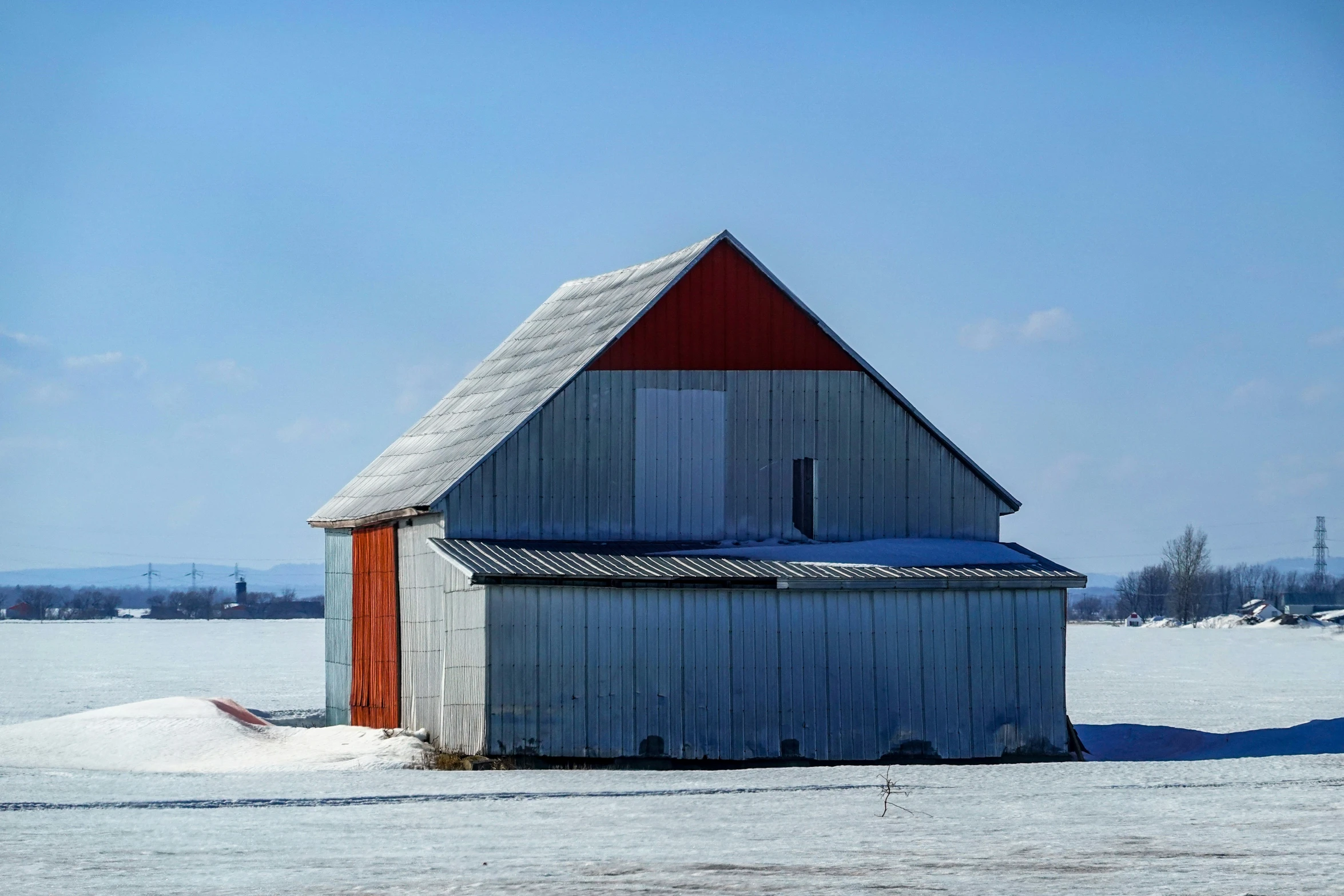 a farm house in a snowy field with snow on the roof