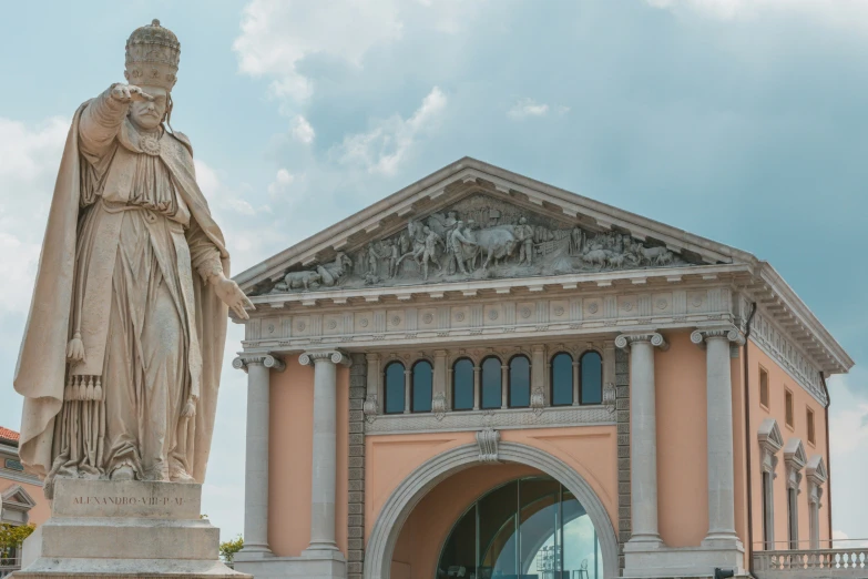 an entrance view of a pink building with a statue next to it