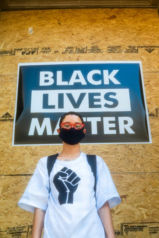 a person with a black mask and a sign that reads, black lives matter