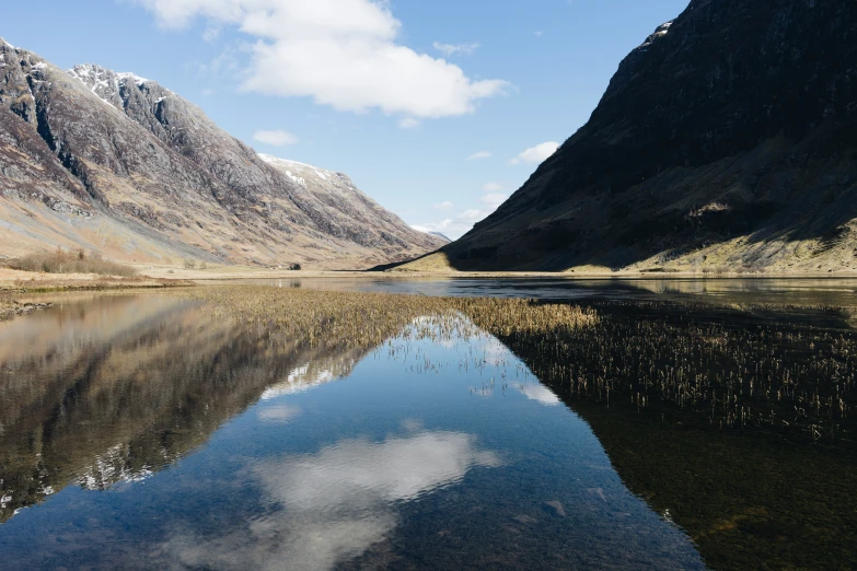 clear, still water near large mountains on sunny day