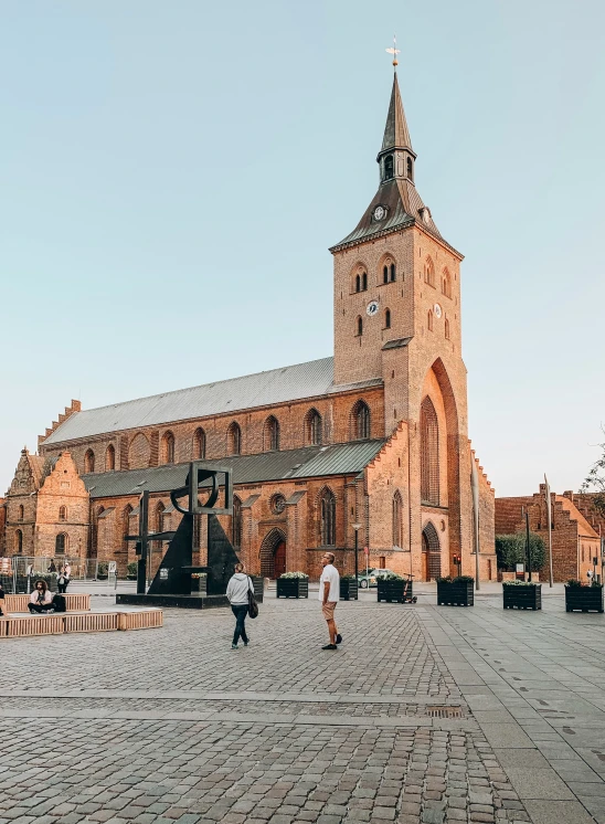 a cathedral with people standing outside of it on a bricked area