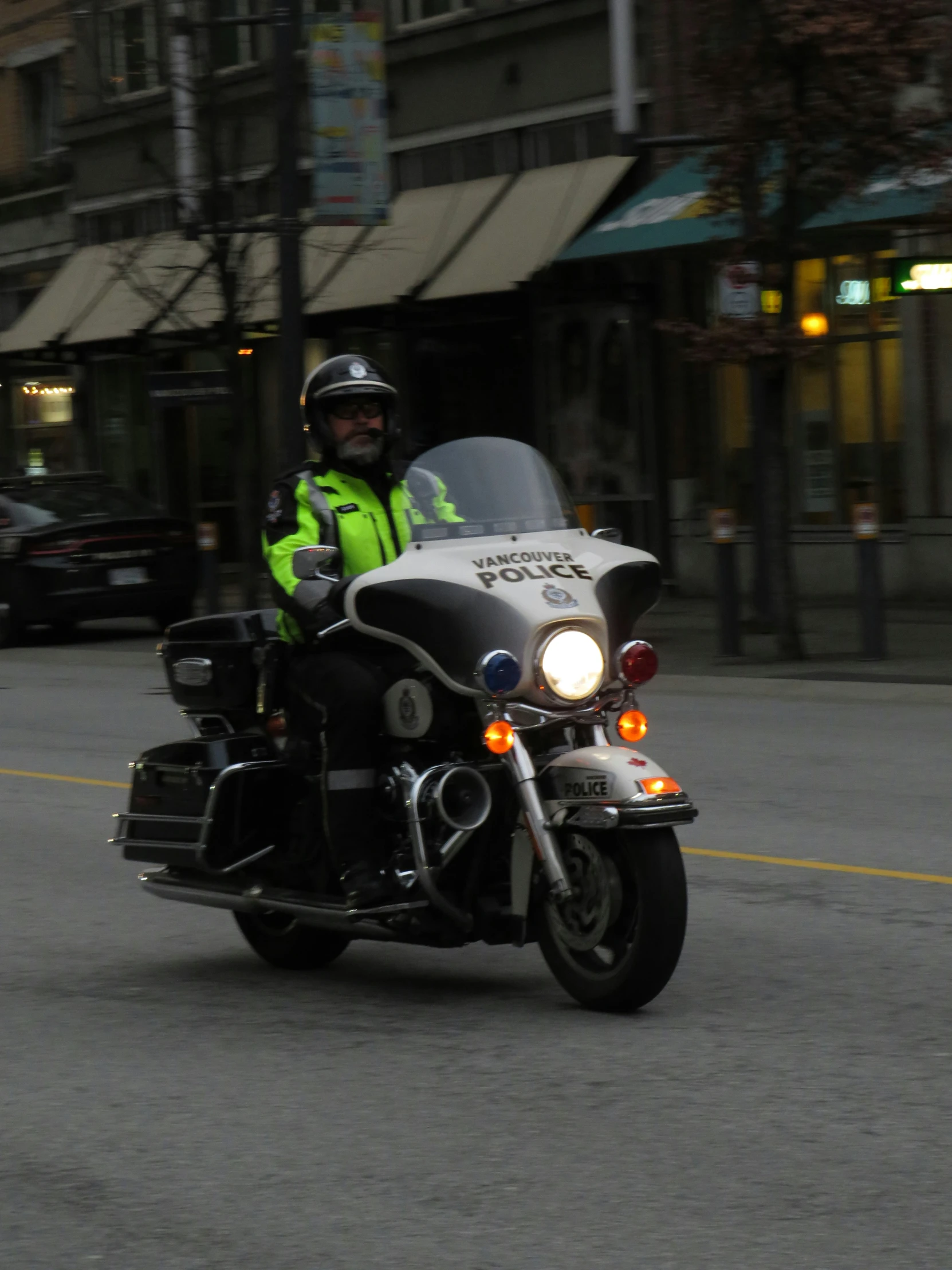 a police officer on a motorcycle wearing neon green is going down the street