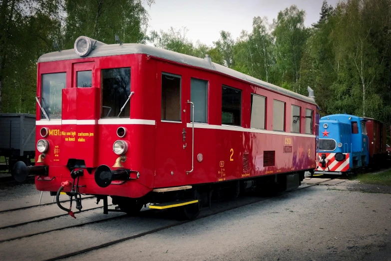 two different colored trains on tracks next to each other