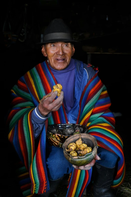 a man with food in his hands is sitting on the ground