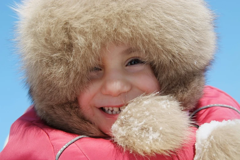 a close - up of a child in winter clothing wearing a hat and smiling