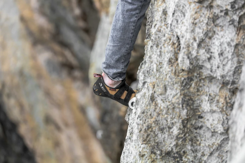 a person climbing up on a rock with their feet on the rock