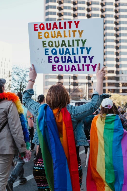 people holding up protest signs during a rainbow parade