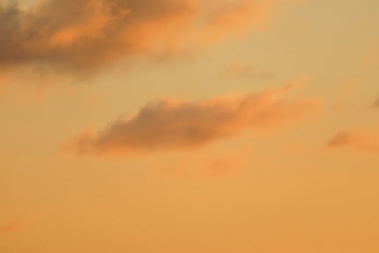 a plane flying high up in the sky at sunset