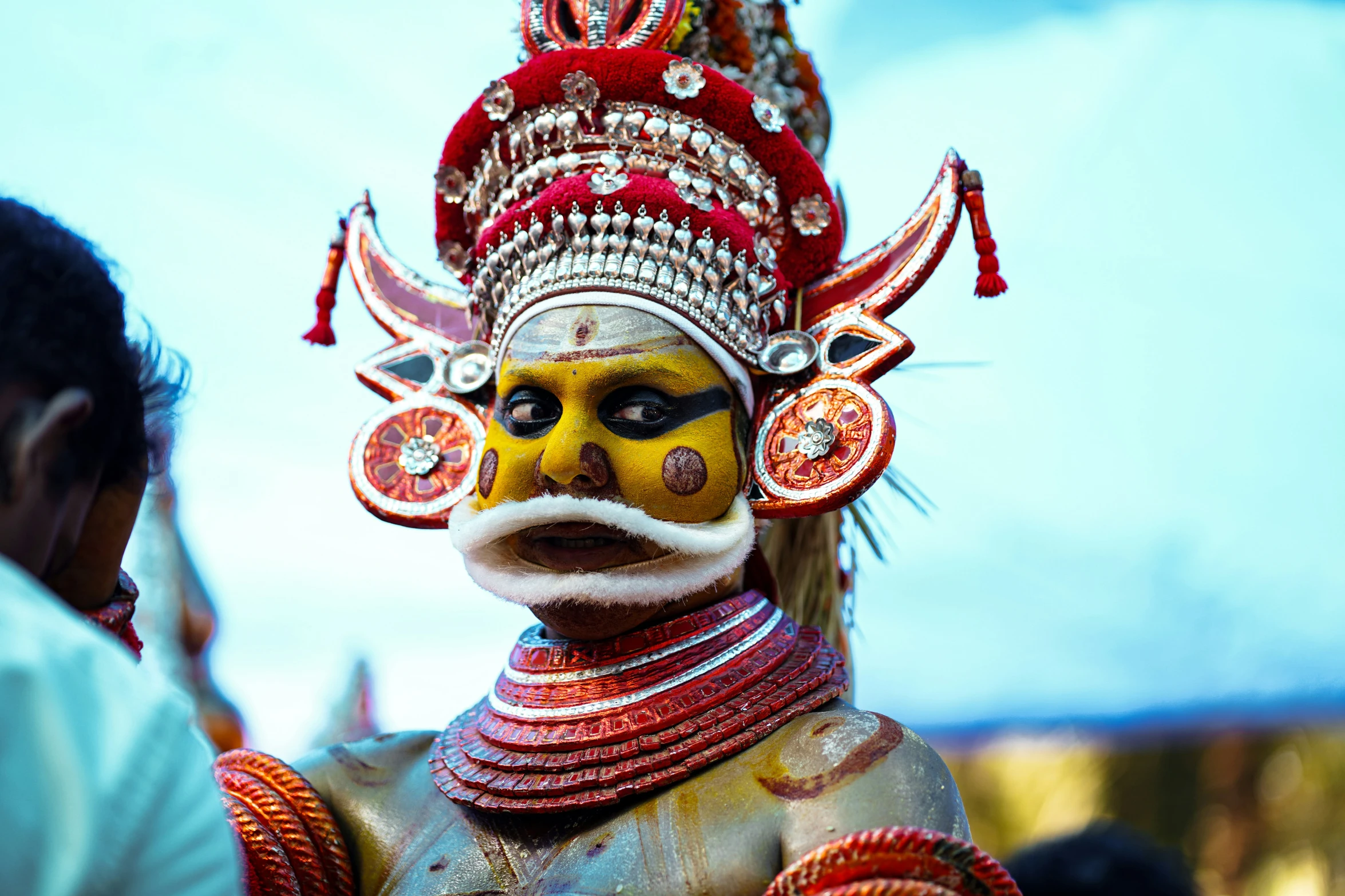 a person standing in front of a man that has a yellow mask on