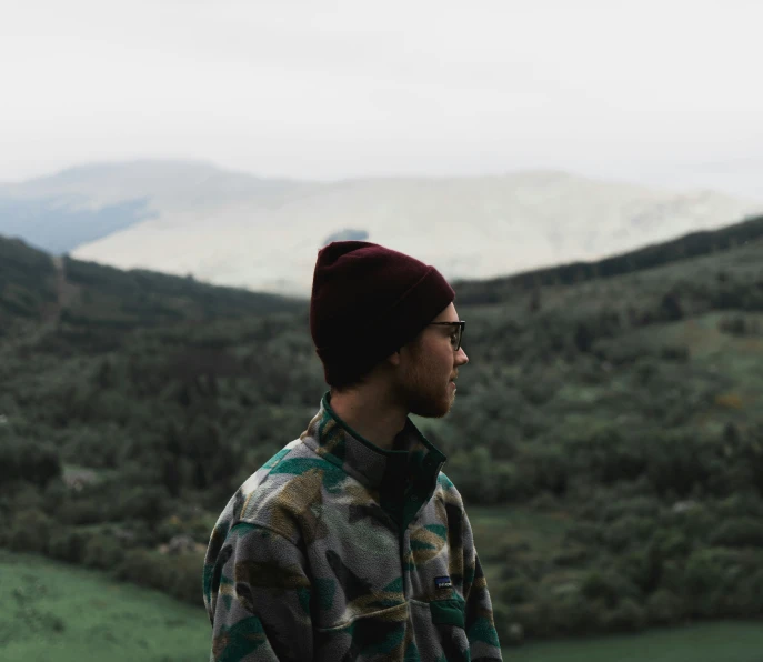 a man with glasses standing on top of a hill