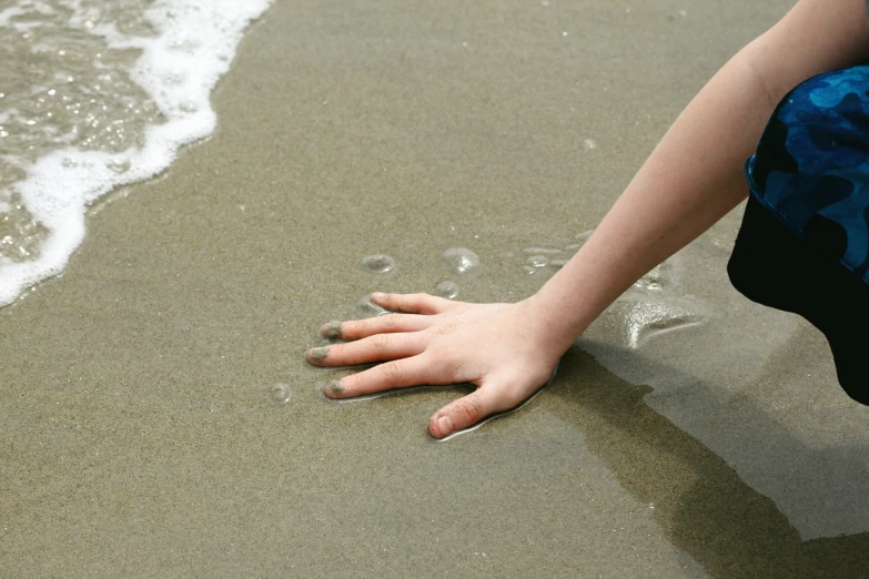 an up close s of a child's hand on a beach