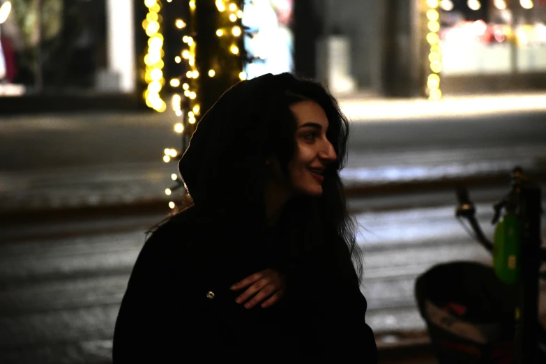 a woman walking down a sidewalk covered in lights