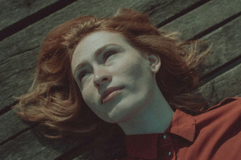 red headed woman laying on a wood bench