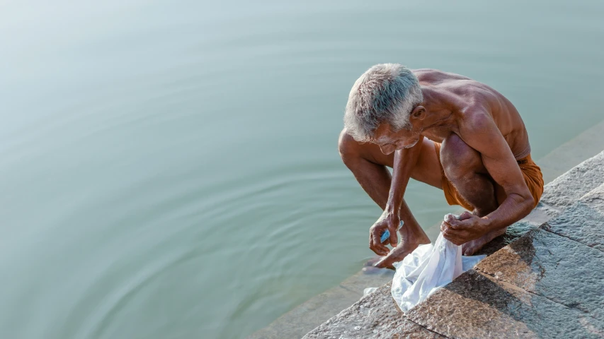 an old man standing on a ledge and holding a paper towel