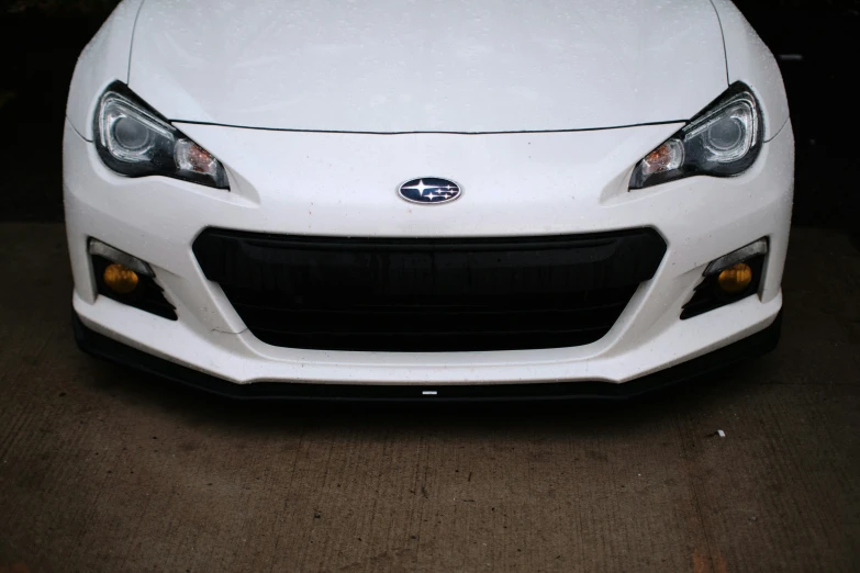 a white car with yellow lights sitting in a driveway