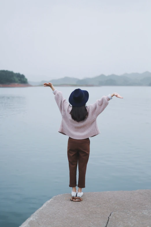 the woman is standing at the end of a pier in the water