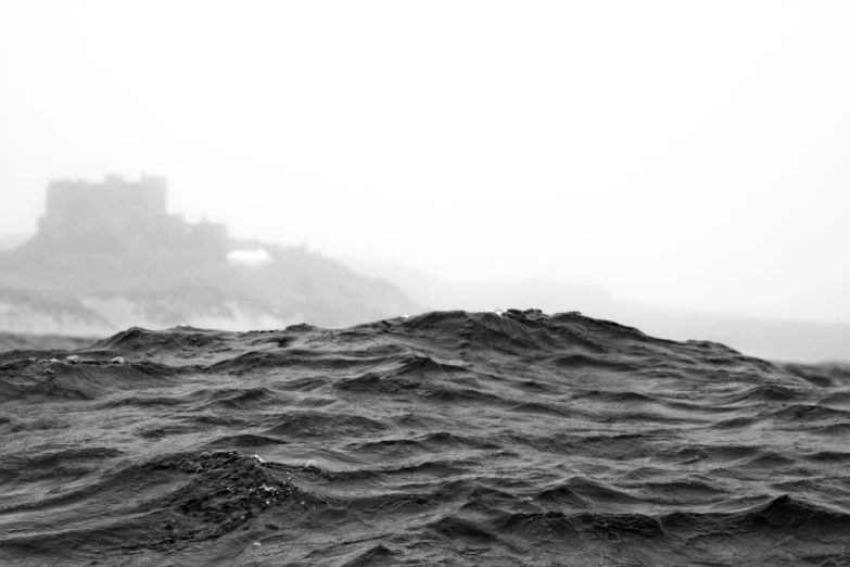 black and white po of a castle in a sea with waves