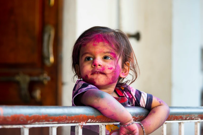 little girl with color on her face standing on a balcony