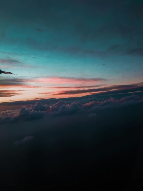 an airplane wing flying in the air over clouds