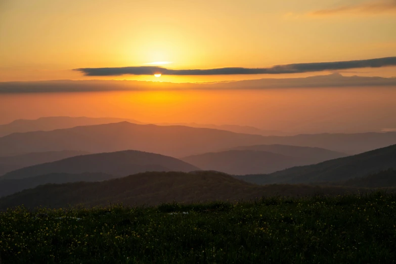 sunrise on mountains overlooking field and forest