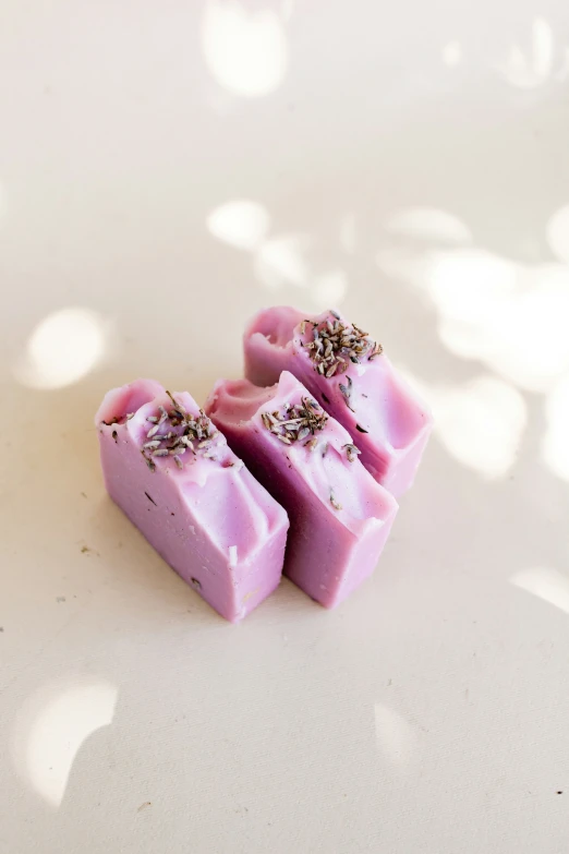 three bars of pink colored soap with various brown things