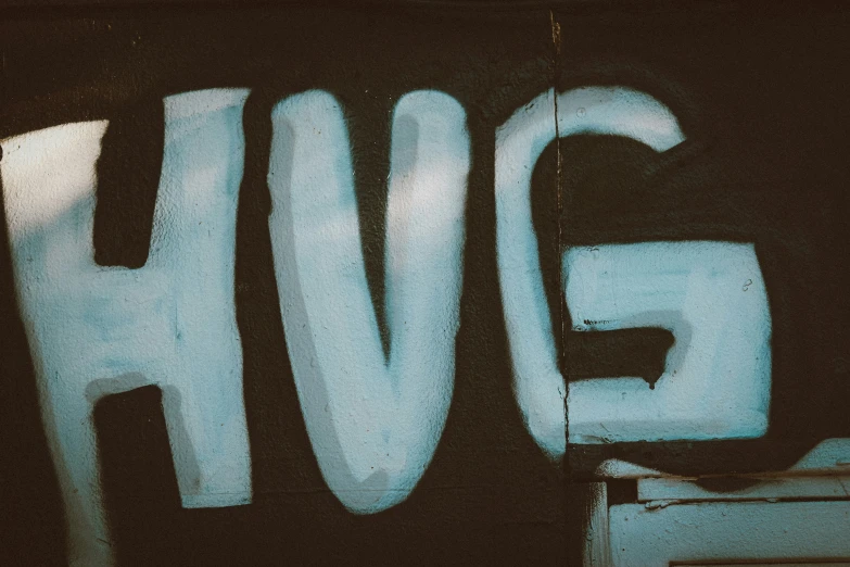 closeup s of a black wall with graffiti writing the word hjh