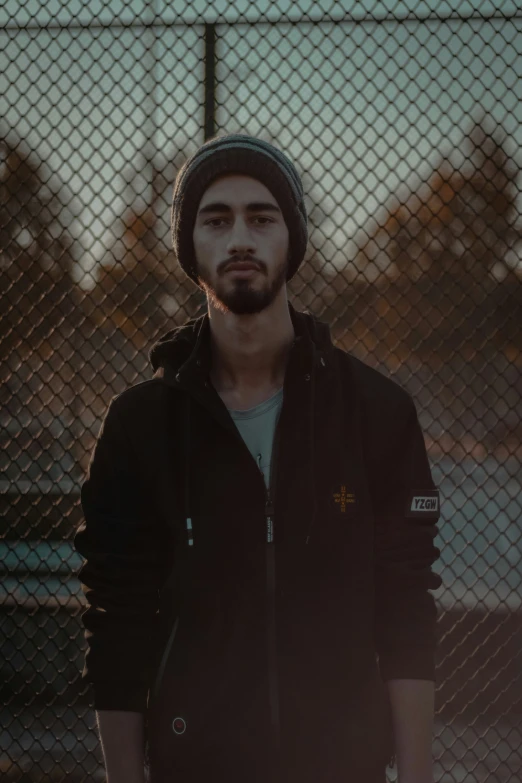 a man standing next to a fence, looking into the camera