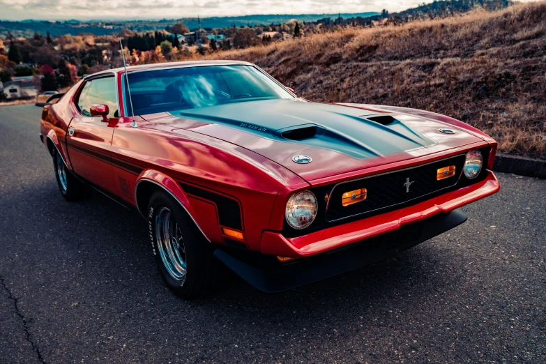 a red and black muscle car sitting on a street