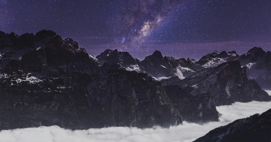 a view of mountains under the stars and clouds