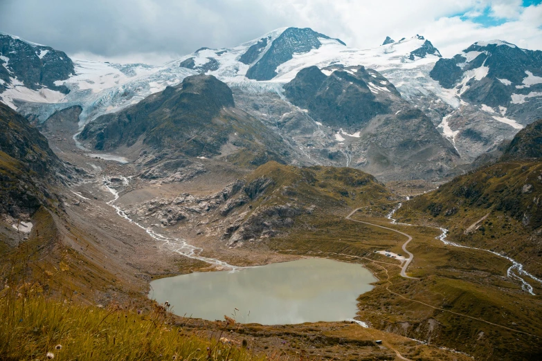 a lake surrounded by snowy mountains on a cloudy day