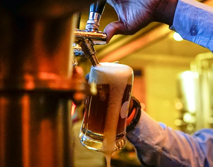 a man is filling beer from a tall glass